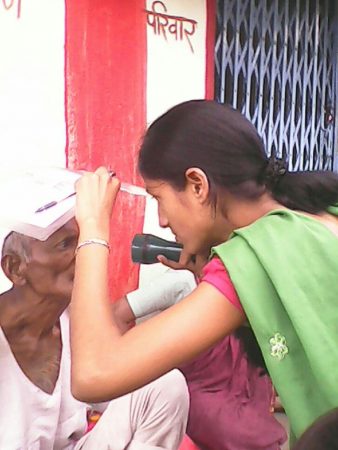 Sarashwati uses a torch light to examine a man’s eyes. 