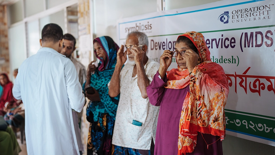 A group of men and women try on eyeglasses in a clinic. 