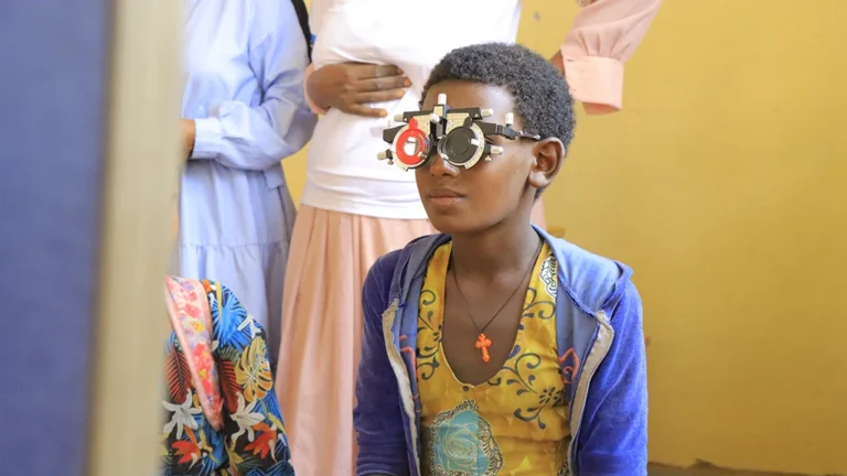 A girl wears a pair of refracting frames while getting an eye exam.